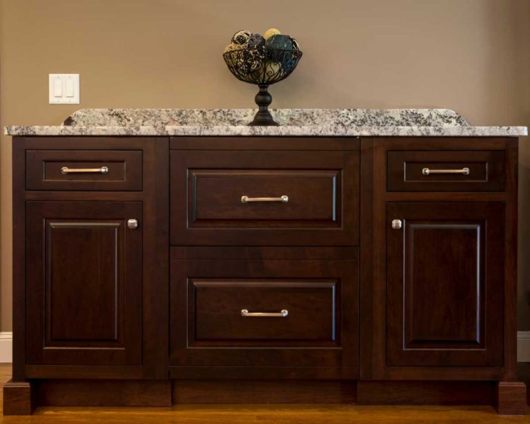 Dark wood built-in cabinet with drawers and a stone countertop.
