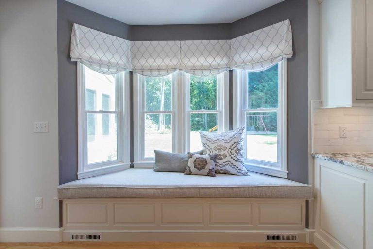 Window seat with built-in drawers beneath a bay window.