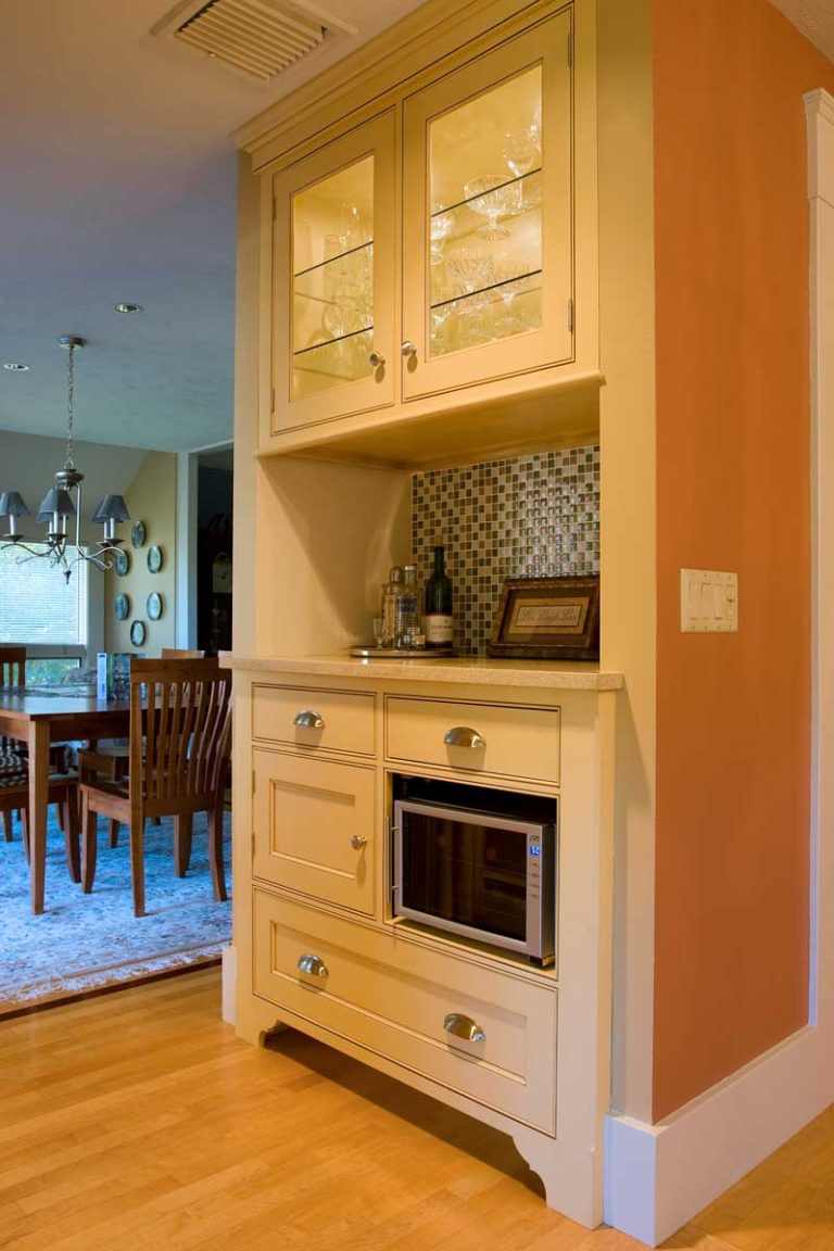 White built-in cabinetry with a microwave and glass-front upper cabinet.