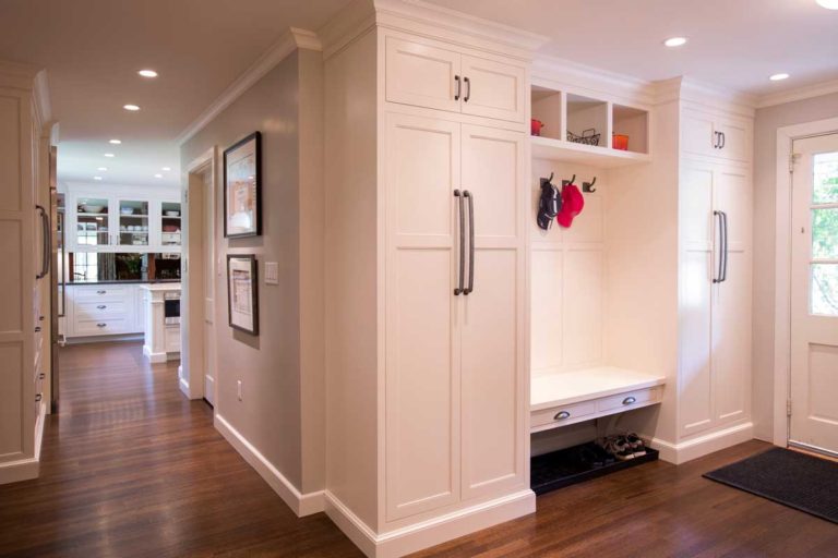 Mudroom with white cabinetry, a built-in bench and coat hooks.