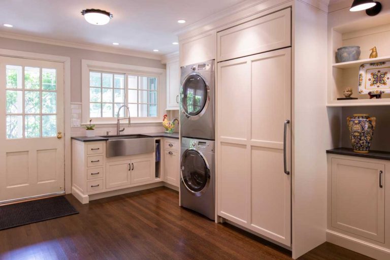 Laundry room with appliances and tall white storage cabinets.