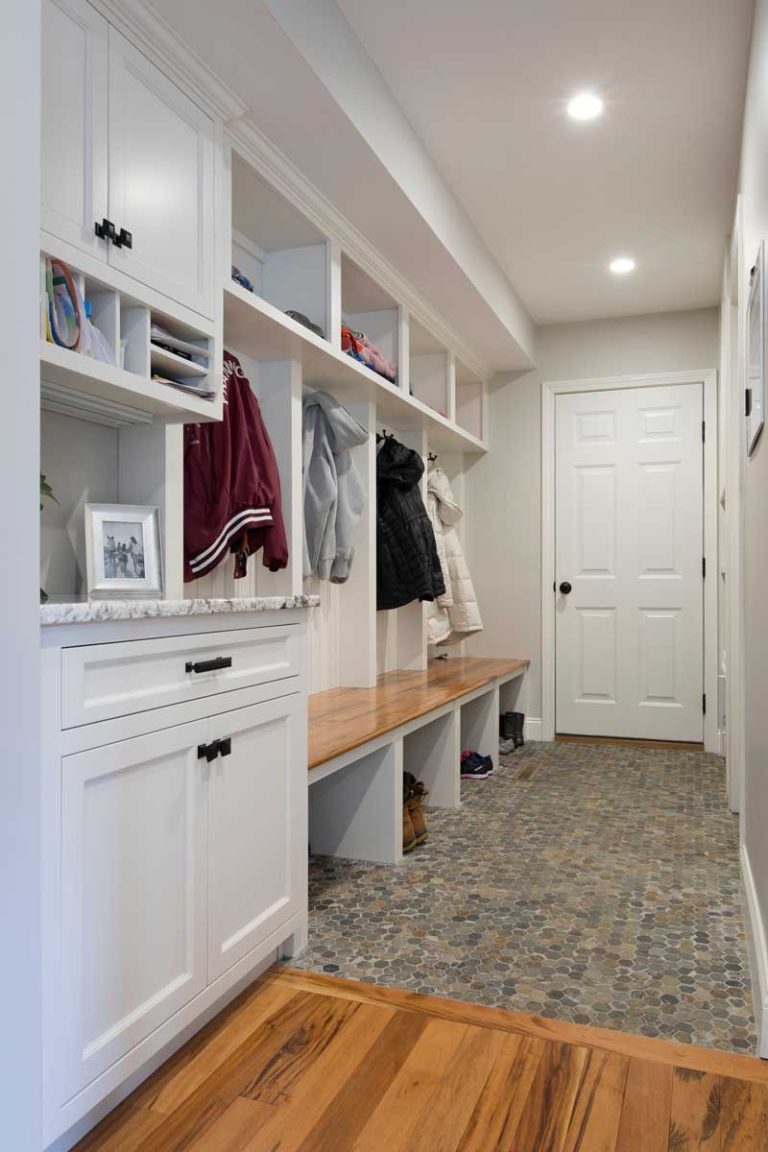White mudroom cabinetry with open cubbies, coat storage and a built-in bench.