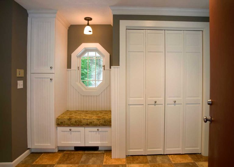 Mudroom with white storage cabinets and a cushioned bench beside an entry door.