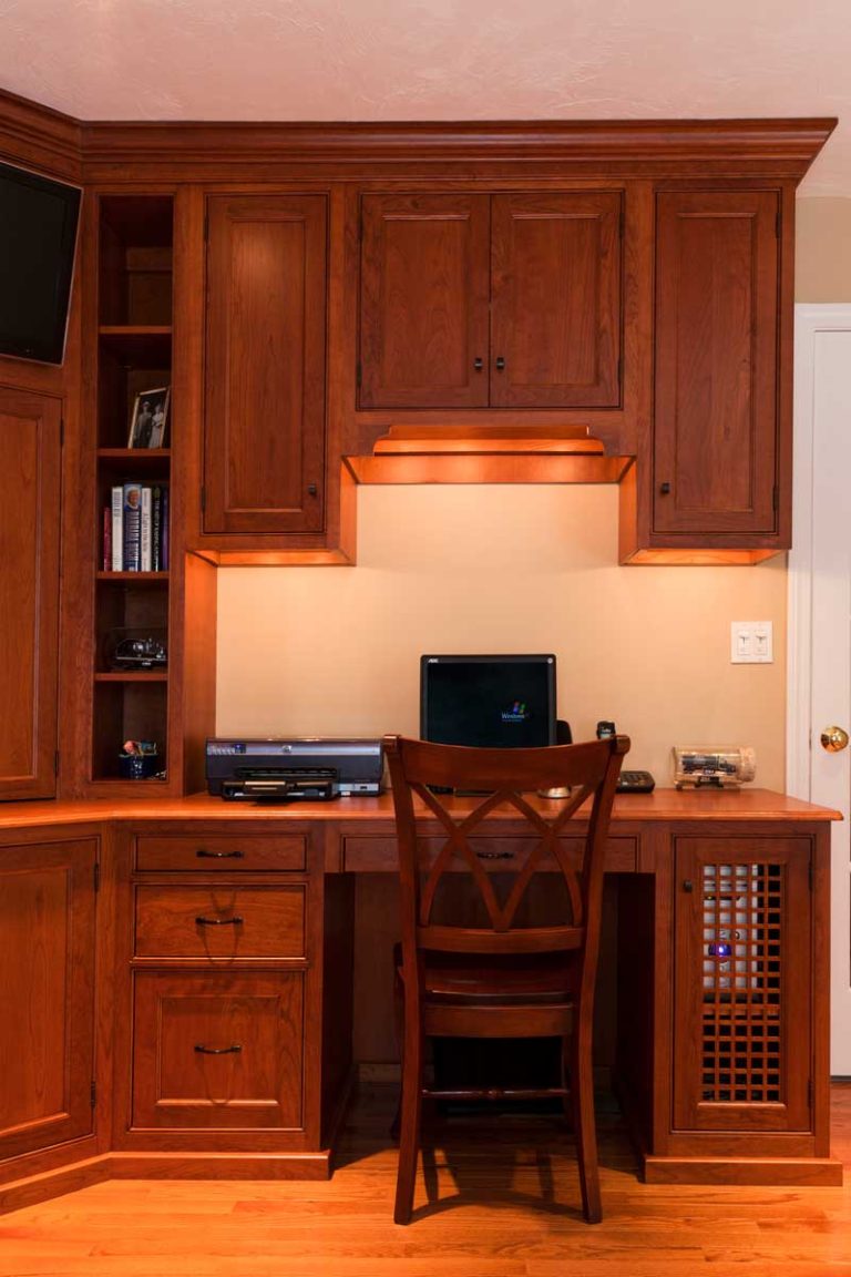 Wood home office cabinetry with a built-in desk and glass-front cabinets.